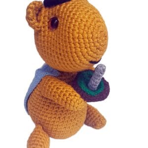 Vista lateral del amigurumi capivara, tejido a crochet con colores naturales y diseño tierno