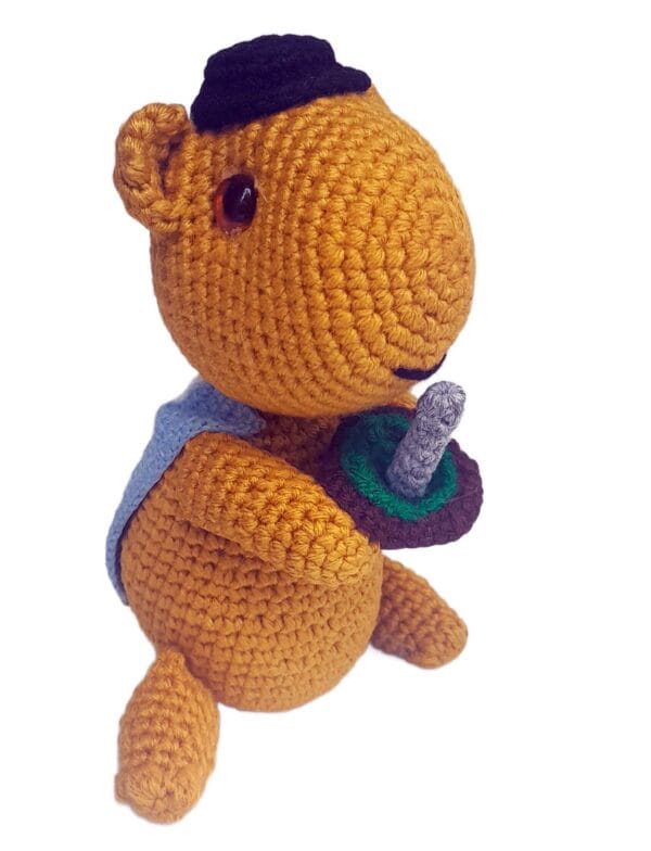 Vista lateral del amigurumi capivara, tejido a crochet con colores naturales y diseño tierno