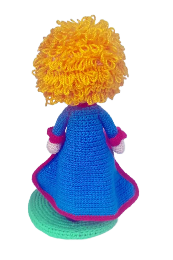 Muñeco amigurumi de El Principito tejido a crochet, con capa turqueza y cabello rubio.
