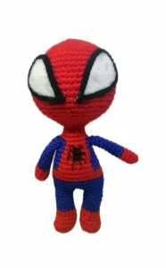el hombre araña Muñeco amigurumi tejido a crochet inspirado en el Hombre Araña, con traje rojo y azul y ojos grandes blancos, sobre fondo blanco.