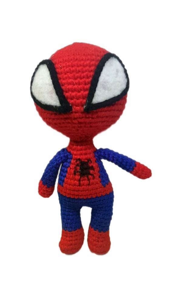 el hombre araña Muñeco amigurumi tejido a crochet inspirado en el Hombre Araña, con traje rojo y azul y ojos grandes blancos, sobre fondo blanco.