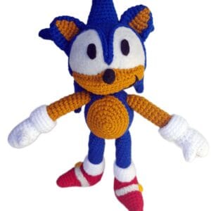 Amigurumi de Sonic tejido a crochet, vista frontal, mostrando su expresión decidida, ojos grandes y zapatillas rojas características, sobre fondo blanco.