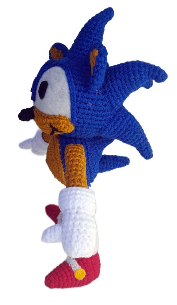 Amigurumi de Sonic tejido a crochet, vista lateral izquierda, resaltando sus púas traseras y las proporciones del cuerpo.