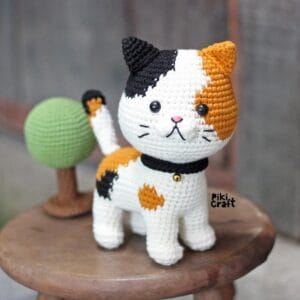 gato amigurumi tejido a crochet sobre un banco de madera