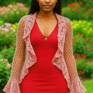 Saco circular tejido a crochet sobre modelo de piel morena con los brazos relajados a los costados, La escena se desarrolla en un jardín florido y luminoso, con colores naturales que enmarcan la prenda sin distraer la atención. El enfoque está en los detalles del tejido y su caída suave sobre el cuerpo.