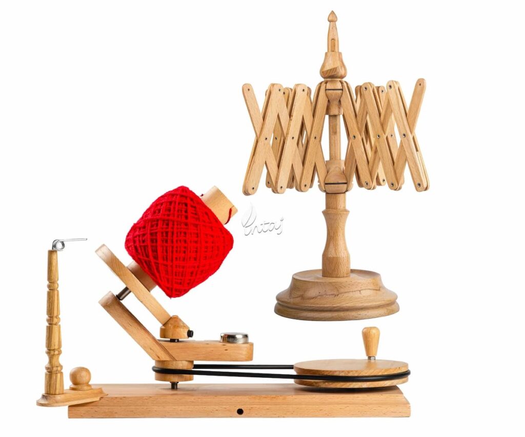 Bobinadora de hilo artesanal en madera de palisandro con devanadora tipo paraguas, mostrando un ovillo rojo en proceso de enrollado sobre base robusta y polea giratoria. Ideal para crochet, tejido y organización de lanas.