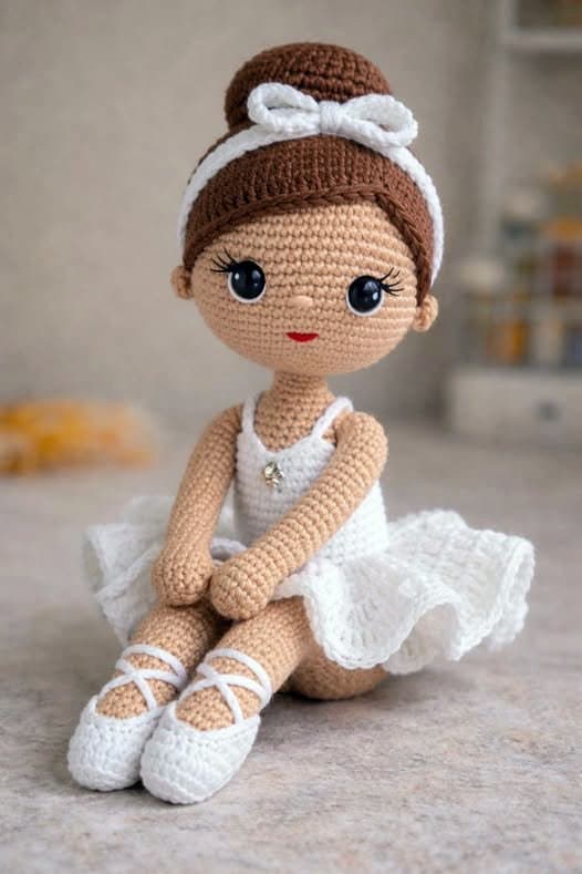 Free Crochet Ballerina Doll Pattern with white tutu, brown hair and blue eyes sitting.